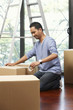 © ImageHit - Man sealing cardboard box with adhesive tape