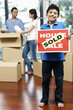 © ImageHit - Boy holding For Sale sign with SOLD on it, man and woman packing in the background