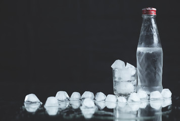 Bottle with glasses of vodka on black background.