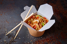 Chinese Noodles With Chicken And Vegetables In A Cardboard Box On A Dark Background, Asian Food Delivery, Concept Of Street Food,  Copy Space