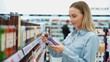 © Grustock - Shopping - young woman holding bottle of shampoo in supermarket