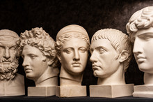 Group Gypsum Busts Of Ancient Statues Human Heads For Artists On A Dark Background. Plaster Sculptures Of Antique People Faces. Renaissance Epoch Style. Academic Subject. Blank For Creativity.