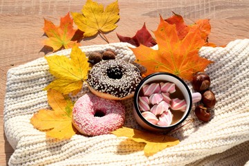 autumn composition: a cup of cocoa with donuts and autumn leaves.