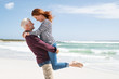Loving senior man lifting woman on beach