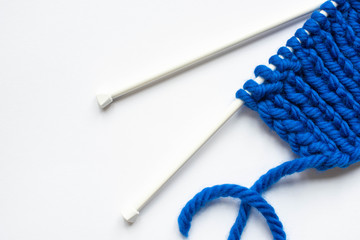 Sticker - top view of blue wool yarn and knitting needles on white background