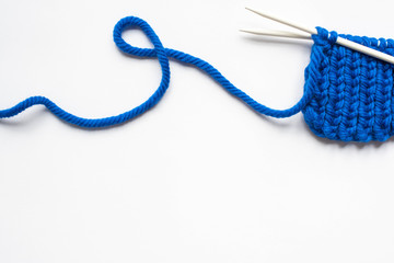 Sticker - top view of blue wool yarn and knitting needles on white background