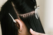 The hairdresser does hair extensions to a young girl in a beauty salon. Professional hair care. Close up of capsules and strands of grown hair