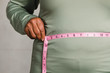 Close up of senior man measuring waist with a tape