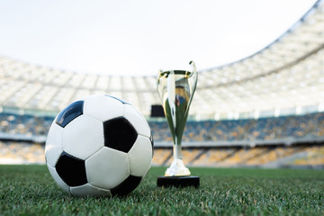 Wall Mural - soccer ball and trophy on grassy football pitch at stadium