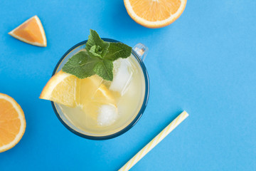 Wall Mural - Orange drink or lemonade with mint and ice  in the glass  on the blue  background. Top view. Copy space.