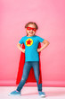 beautiful little girl in superhero costume in red Cape and mask shows how strong
