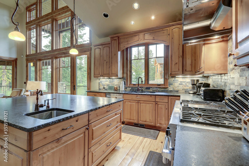 Cuadros en Lienzo Large luxury kitchen interior with light wood hardwood floor and dark granite slab on island with huge windows