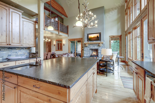 Fotografía Large luxury wooden kitchen interior with light wood hardwood floor and dark granite slab on island with huge windows