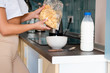 © LIGHTFIELD STUDIOS - cropped view of african american woman holding pack with cornflakes near bowl and bottle with milk