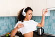 © LIGHTFIELD STUDIOS - attractive african american girl in wireless headphones holding toast bread with jam and cup of coffee