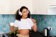 © LIGHTFIELD STUDIOS - happy african american girl in wireless headphones holding toast bread with jam and cup of coffee