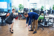 © Михаил Решетников - Colleagues play sports during the break. Health care concept at work. Middle managers in business suits doing fitness exercises in an open space office. Woman in high heels doing squats.