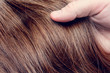 © Анастасия Семашко - Man's hand holds a beautiful wavy hair, brown hair, close up