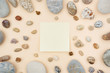 Sticky notes in the middle of mix of rounded multicolor textured stones on beige paper background . Flat lay with copy space