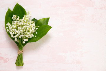 Wall Mural - bouquet of flowers lily of the valley on pink table, top view, space for text, flat lay.