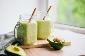 Wall Mural - creamy smoothie from avocado and banana in glass cups with paper tubes on a light background. no plastic. healthy food