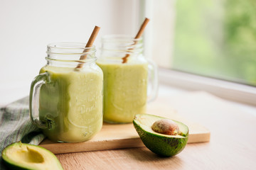 Wall Mural - creamy smoothie from avocado and banana in glass cups with paper tubes on a light background. no plastic. healthy food