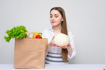 Girl with cabbage, grocery shopping bag full of fresh vegetables, white background, copy space. Concept of vegan lifestyle