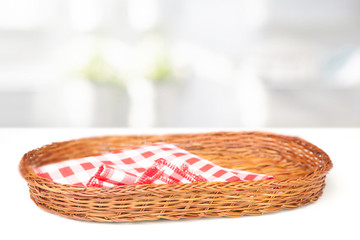 Wall Mural - 
Oval-shaped wicker basket and checkered cotton napkin inside on a white table table