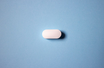 one medical pill isolated on a blue background.