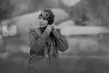 Retro Style Black And White. A Young Female Pilot In Uniform Of Soviet Army Pilots During The World War II. Military Shirt With Shoulder Straps Of A Major, Parachute, Flight Helmet And Goggles.