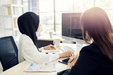 Wall Mural - multiethnic asian female muslim workers working in office as team using computer to strategize and planning work, concept of diversity of culture different race type of people co-working together