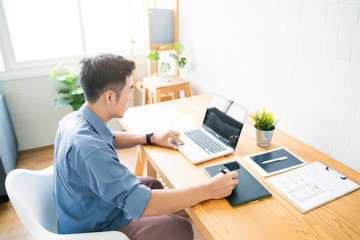 Fototapete - Working from home web designing graphical user interface UX UI, home office using computer laptop and pen sketching graphics tablet device creative planning innovative ideas, asian man quarantine