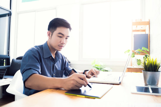 Working from home web designing graphical user interface UX UI, home office using computer laptop and pen sketching graphics tablet device creative planning innovative ideas, asian man quarantine