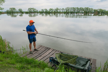 Wall Mural - Feeder fishing. Fisherman in action, angler catch fish at lake pond