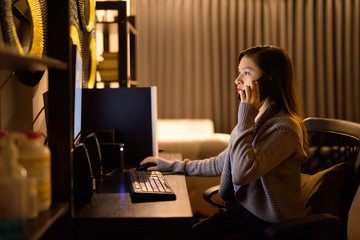 Young Asian woman talking on the phone while working from home