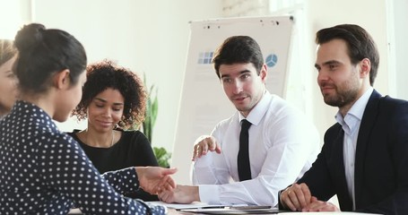 Canvas Print - Smiling diverse business people gathered at table, discussing project ideas at brainstorming meeting in office. Millennial female indian employee consulting mixed race colleagues at workplace.