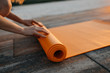 Young woman rolling yoga mat in the evening, after exercise. Yoga instructor outdoors.