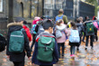 Happy primary asian, india, Chinese, africa & american Caucasian student, kids, pupils & teacher carrying  school bags on their way in rain winter day, with red maple leaves