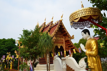 Wall Mural - Praying statue in front of the beautiful temple of Wat Phra Singh in Chiang Rai