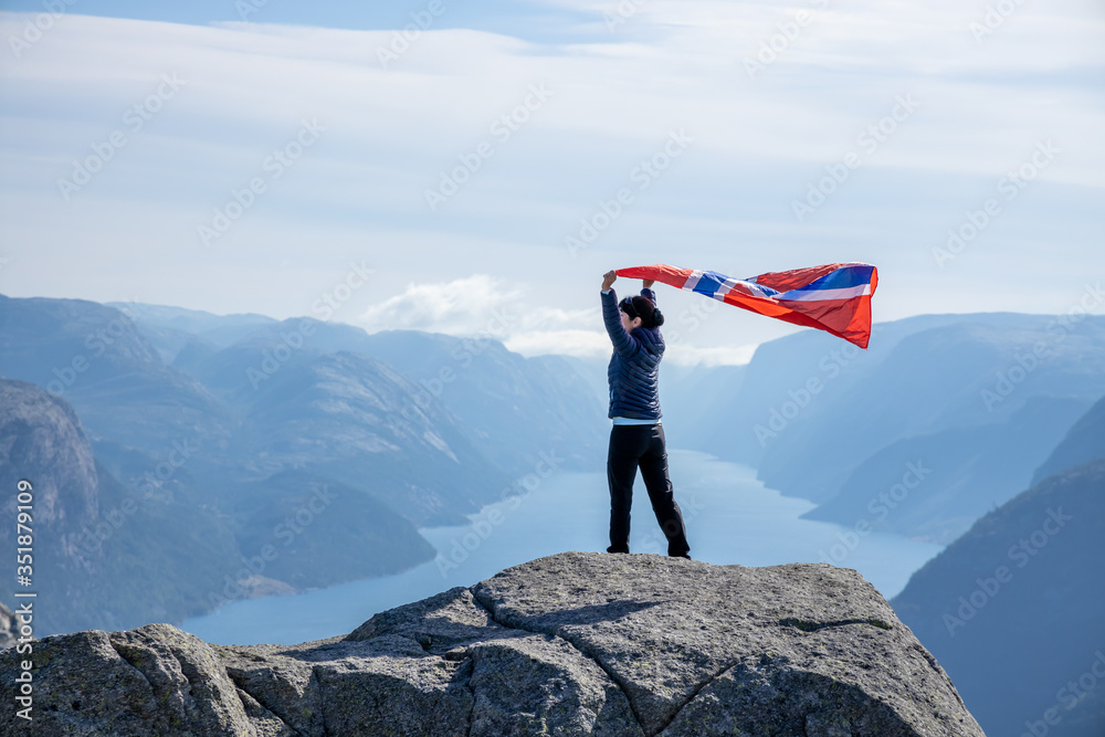 Woman with a waving flag of Norway on the background of nature - obrazy, fototapety, plakaty 