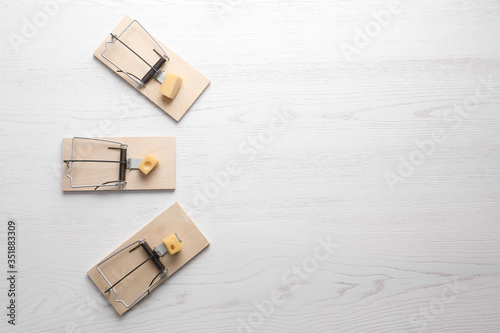 Cuadros en Lienzo Mousetraps with pieces of cheese and space for text on white wooden background, flat lay