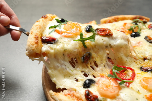 Fotomural Woman taking slice of cheese pizza with seafood at table, closeup