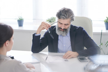 Wall Mural - Aged pensive male hr manager holding eyeglasses by temple while reading resume