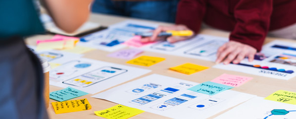 Poster - Close up ux developer and ui designer brainstorming about mobile app interface wireframe design on table with customer brief and color code at modern office.Creative digital development agency.panning