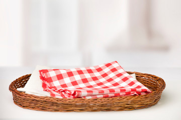 Wall Mural - 
Wicker oval basket with a red checkered cotton napkin inside and beige on a white table