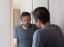 Man Looking Anxious In Bathroom Mirror