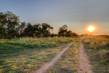 Summer sunset over field and road near bank of Volga River opposite village of Emmaus, near the town of Tver, Russia.