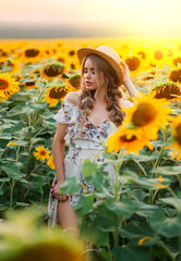 photo beauty woman model, blooming field. Rural fashion image. Yellow flowers sunflower. Blonde hair two braids, boater straw hat on head. Blurred backdrop bright sunny fantasy summer orange sunset