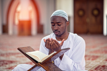 Religious black muslim man praying inside the mosque