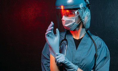 Wall Mural - female doctor with a stethoscope on her neck, in a medical mask and glasses on her face on a dark background